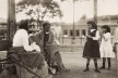 Duas mulheres, uma de costa, descansando em banco de praça, 1910