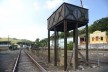Reservatório de água em estrutura metálica no itinerário ferroviário, ao fundo edificações de interesse cultural