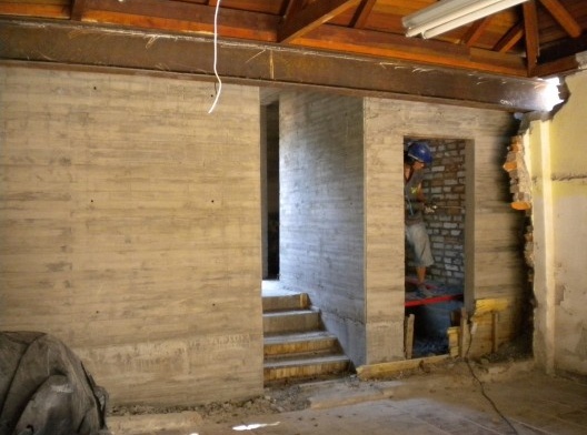 Substituição das paredes da edícula, que suportavam a cobertura, por viga de aço corten. Ao fundo, paredes de concreto à vista do arquivo e serviços, totalmente independentes da edícula