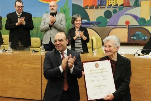 Rosa Kliass recebe o título de Cidadã Paulistana do vereador Police Neto, autor da iniciativa; ao fundo, Lucia Costa, autora do texto