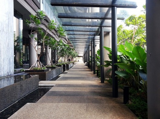 Calçada do edifício ParkRoyal, em Cingapura. Destaque para a cobertura de vidro e a vegetação junto à rua