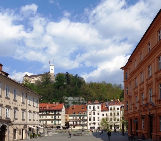 Centro de Ljubljana, em perspectiva do largo para a margem do rio Ljubljanica, vendo, ao alto, o castelo