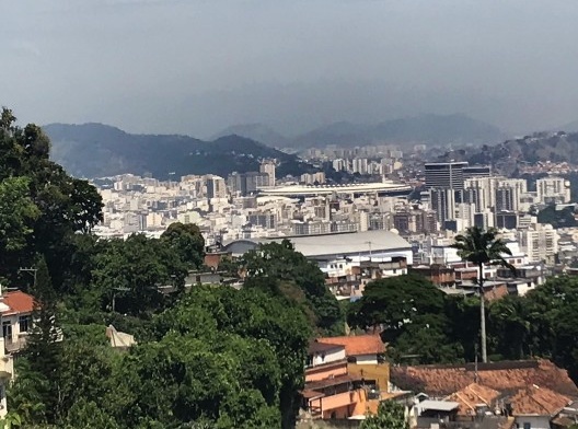 Vista a partir da rua Almirante Alexandrino. No primeiro plano o casario que desce a rua Eliseu Visconti. Mais adiante a comunidade do Fogueteiro, destacando-se o grande volume de sua quadra. Depois o Maracanã e Vila Isabel mais à esquerda. Depois Riachue