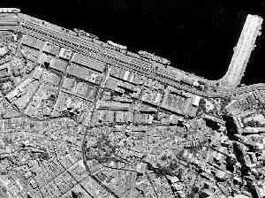 Figura 1 – Foto aérea (geral e zoom) da área portuária permitindo perceber o tecido urbano na região mais elevada, como ocupação predominante do século XIX e as áreas aterradas no início do século XX, ocupadas pelos galpões industriais