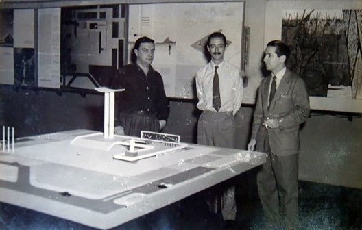 Em primeiro plano a visão da maquete do projeto vencedor do concurso do monumento e, ao fundo, da esquerda para a direita, o escultor Alfredo Ceschiatti, o arquiteto Hélio Ribas Marinho e o arquiteto Marcos Konder