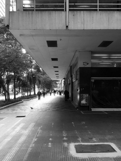 A proteção do passeio público proporcionada pela projeção das varandas existentes no embasamento comercial do Edifício Metrópole (1959) de Salvador Candia e Gian Carlo Gasperini e passagem existente no térreo do Edifício Conde Silvio Penteado (1951) de Ri