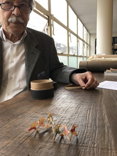 Paulo Mendes da Rocha, com o bilhete de Flavio Motta em mãos e em primeiro plano os bonecos feitos por Naná