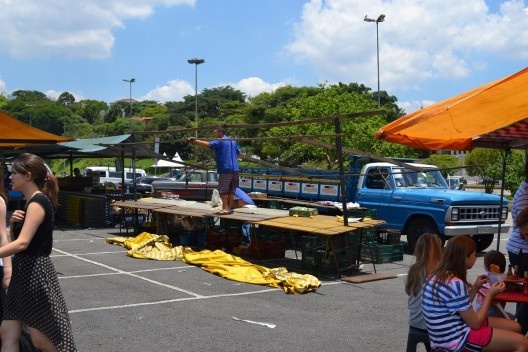 Processo de desmontagem de uma barraca: estrutura do telhado exposta, feita por “cumeeira” e “terças” em madeira, note-se que sem a cobertura, a estrutura entra em desalinhamento