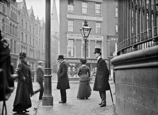 Imagem do flâneur. Homem com guarda-chuva em pé na junção das ruas Nassau, Grafton e Suffolk, c.1900