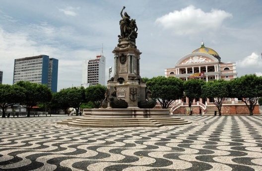 Desenho das ondas na praça São Sebastião, em Manaus/AM. Em primeiro plano o monumento à abertura do porto. Ao fundo, o Theatro Amazonas