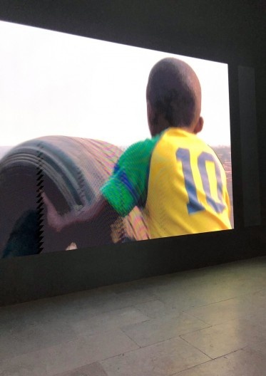 Francis Alÿs, The nature of the game, Pavilhão nacional da Bélgica. La roue, video realizado em 2021 no morro de escórias da mina de cobalto Etoile du Congo, Lubumbashi: um menino empurra por horas morro acima um enorme pneu pela alegria de