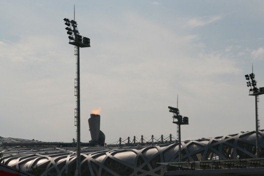 Estádio Olímpico de Pequim, o \"Ninho de pássaro\", com tocha olímpica ao fundo. Arquitetos Jacques Herzog e Pierre De Meuron