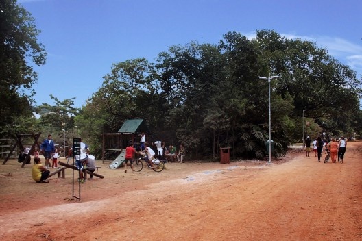 Playground com brinquedos padrão da prefeitura e caminhos não pavimentados