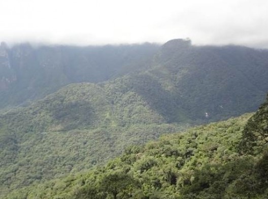 Foto tirada do trem nas proximidades do km 62, ao longe, a ferrovia serpenteia na densa da floresta atlântica