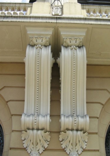 Par de mísulas no nível térreo da fachada, e mureta da balaustrada com adorno em forma de lira.