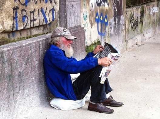 Homem lendo jornal sentado ao chão, rua Caio Prado, São Paulo