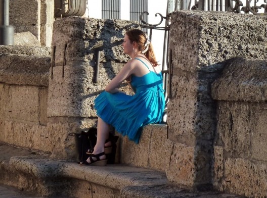 Eis que avistam uma bela moça de vestido azul sentada no banco de pedra de uma ponte sobre o rio.