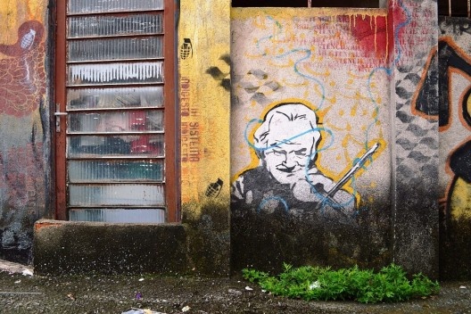 Córrego oculto, diversas figuras em graffiti habitam as paredes da viela como se ali estivessem desde sempre