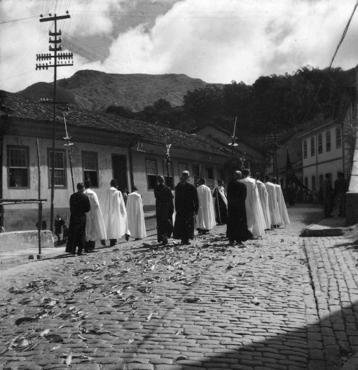 Procissão da Ressureição passando pela Rua Getúlio Vargas, destacando-se ao cento, na parte inferior, a presença das folhagens formando um tapete para a passagem da procissão