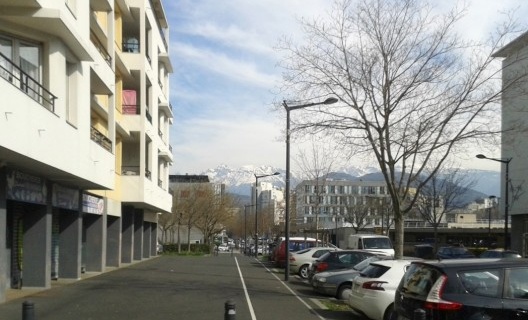 Ruas do bairro de Villeneuve com os Alpes ao fundo. De qualquer lugar que se esteja em Grenoble pode-se ver as montanhas, que praticamente cercam a cidade e permanecem com neve a maior parte do ano