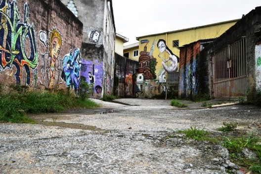 Córrego oculto, na irregularidade do piso cimentado, poças trazem à superfície as águas paradas da área brejosa