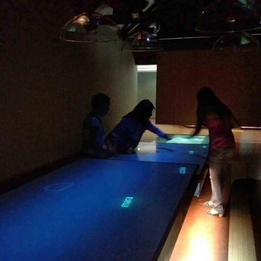 As instalações Palavras Cruzadas e Beco das Palavras, com seus dispositivos luminosos em destaque no ambiente escuro, Museu da Língua Portuguesa, São Paulo