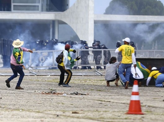 Manifestantes lançam pedras portuguesas contra policiais durante os ataques de 8 de janeiro de 2023