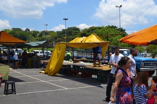 Processo de desmontagem de uma barraca: retirada da cobertura que é desacoplada das pontas das terças da estrutura da cobertura