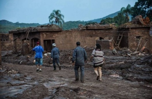 Moradores caminham pelos escombros após rompimento de duas barragens da mineradora Samarco, Mariana MG