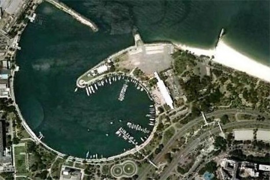 Vista aérea; a ocupação do espelho d’água se dá com uma via sobre o enrocamento ao longo da enseada (o qual já não é visível), estendida, entre 2006-2011, desde o trecho fronteiro ao pavilhão da marina até o início do Parque