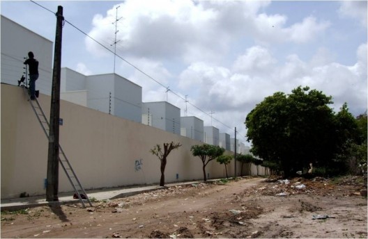 Aspecto externo do condomínio Maison Blanc em meio a vias sem pavimentação