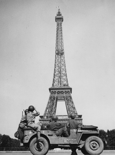 Soldados americanos olham a bandeira tricolor da França hasteada na Torre Eiffel