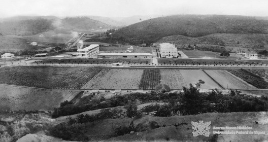 Vista parcial da ESAV na década de 1920, com a avenida da Reta, posteriormente denominada avenida P. H. Rolfs, a linha férrea da Leopoldina, e as edificações: Casa de Hospedes, Alojamento, Prédio Principal, Reitoria e Escritório