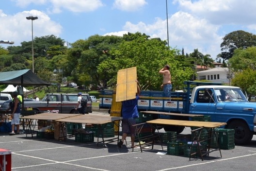 Processo de desmontagem de uma barraca: “tampo” da mesa, seccionado transversalmente em 4 partes, cada parte é dobrada e compactada no caminhão