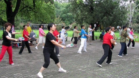 Senhoras dançam ao som de música tradicional chinesa. A bolinha sobre a raquete não pode cair no chão!