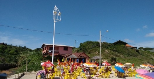O novo sistema de iluminação pública da praia em panorama diurno, ao lado de antigo poste