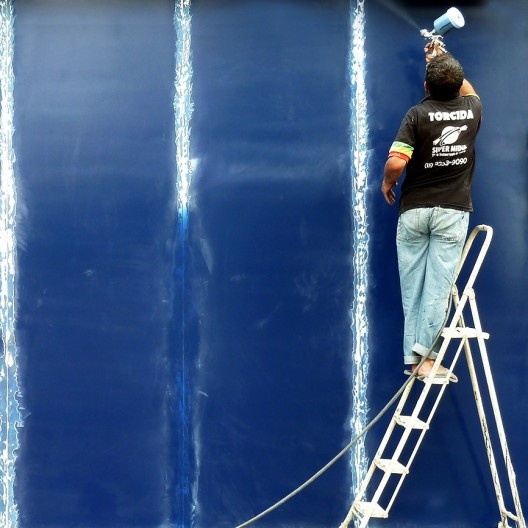 Ego grande, o artista de obra manda antes seu auxiliar lixar e rabiscar o gride que servirá de base para a obra de arte.