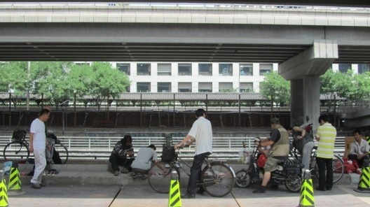 Contraste: sob o viaduto, do outro lado da rua do edifício elegante, a população local faz seu “mercado das pulgas”