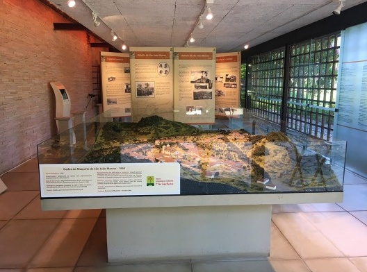 Interior do Centro de Memória com maquete em escala, totens digitais e informações sobre a história da cidade