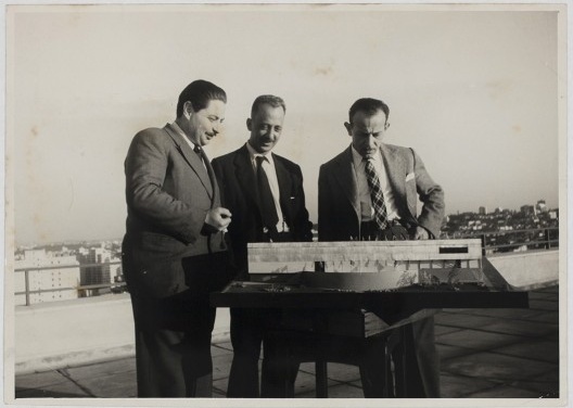 Luís Saia entre Arturo Profili, responsável pela Seção de Imprensa e Propaganda, e Biagio Motta, administrador da 1ª Bienal, e a maquete da sede da 1ª Bienal