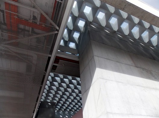 O teto do anexo, onde os elementos estruturais e os sistemas prediais são revelados pela tênue grelha metálica do forro