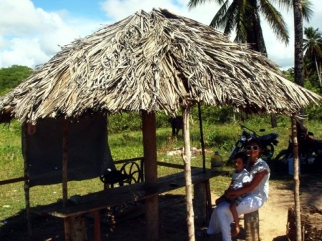 Yara e Pedro esperando a balsa chegar numa sombrinha