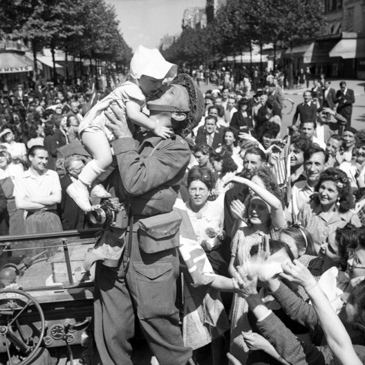 Um fotógrafo da AFPU beija uma criança na liberação de Paris, 26 de agosto de 1944