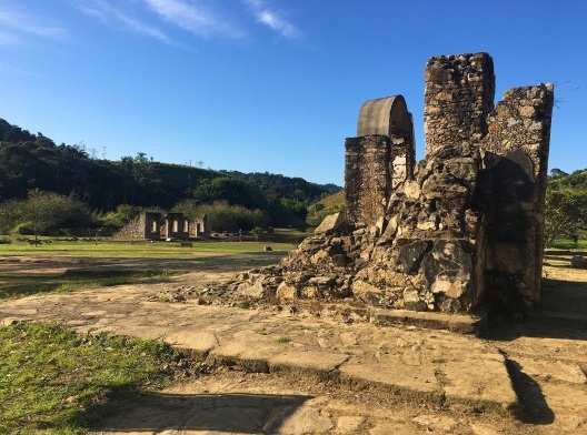 Ruínas da fachada lateral da Igreja Matriz e da calçada em pé de moleque. Ao fundo pode-se observar a casa do capitão-mor