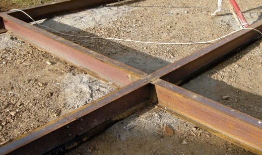 Colocação das vigas tipo I sobre placas de aço assentadas sobre lastro compactado e colocação dos painéis da plataforma no canteiro de obras
