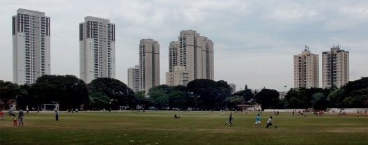 Antiga área de treinamento com gramado do Peão do Prado e raia de areia preservadas. Ao fundo novos edifícios retratam verticalização da região
