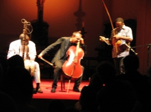 Ballaké Sissoko (Mali) tocando Cora, instrumento erudito africano; Vicent Segal (França), ao violoncelo; Naná Vasconcelos (Brasil), ao berimbau
