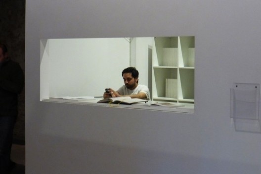 O guardador de objetos, entretido com o celular, não percebe uma pessoa dissimulada na penumbra