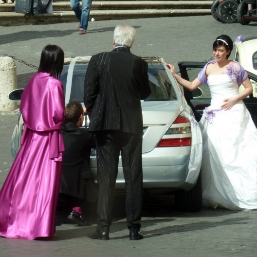 ou nas cores cardinalícias de gosto duvidoso nas roupas de convidada e fotógrafo na saída da igreja em Roma.