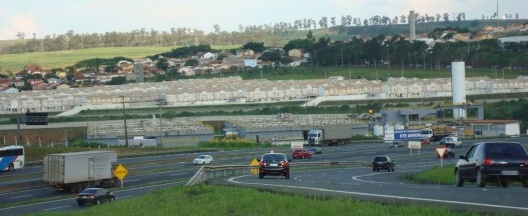 Imagem da Rodovia Dom Pedro I no primeiro plano, estação de tratamento de esgoto em segundo plano e o empreendimento Vila Naturale em terceiro plano